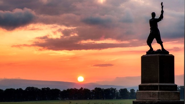 A stone and bronze monument in the sunset