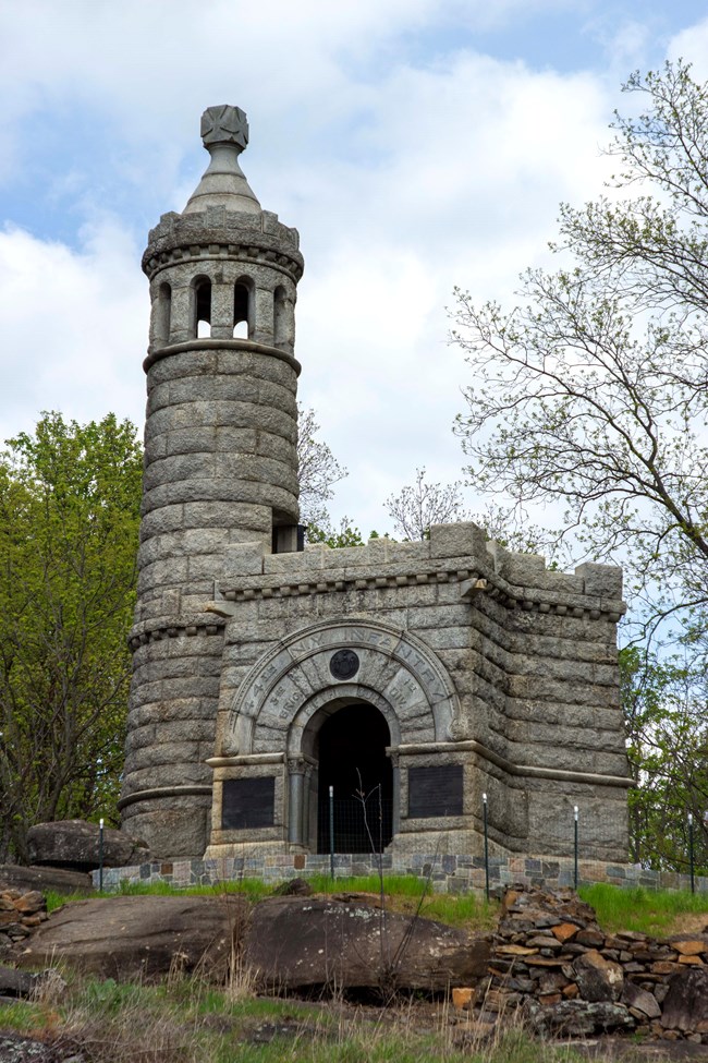 A monument that looks like a small castle sits a top a hill