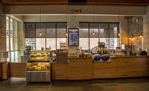 The Battlegrounds Cafe offers food and drink for park visitors. There is a cooler and a long counter and a menu sign.