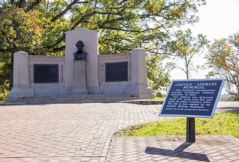 The Lincoln Speech Memorial consists of a bust of Abraham Lincoln and bronze panels are on either side.