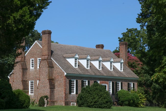 a brick house surrounded by trees and shrubs