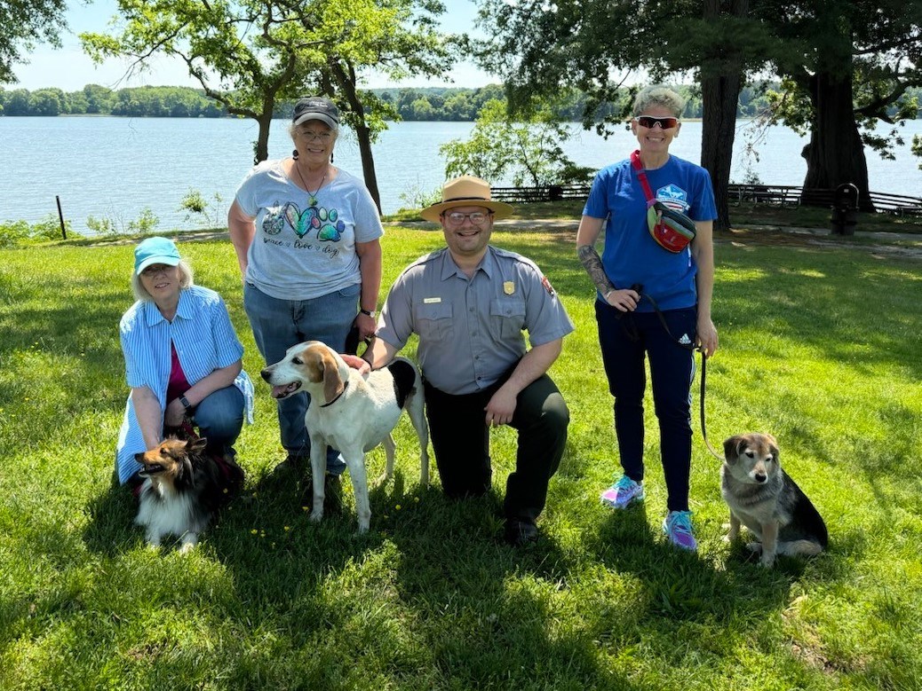 Visitors with their dogs pose for a picture with a park ranger.