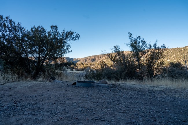A picture of an almost primtive campsite, there is metal ring around a spot making a fire ring.
