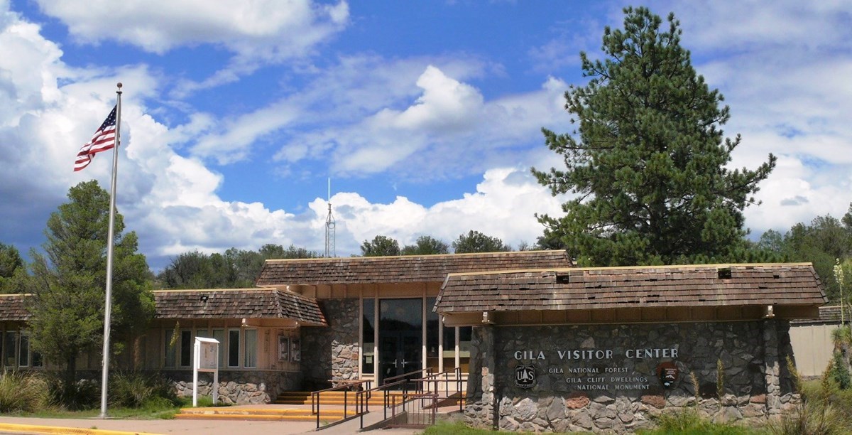 one story building with American flag in front and tall pine tree in the backdrop