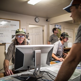 Rangers work at computers and help waiting visitors.