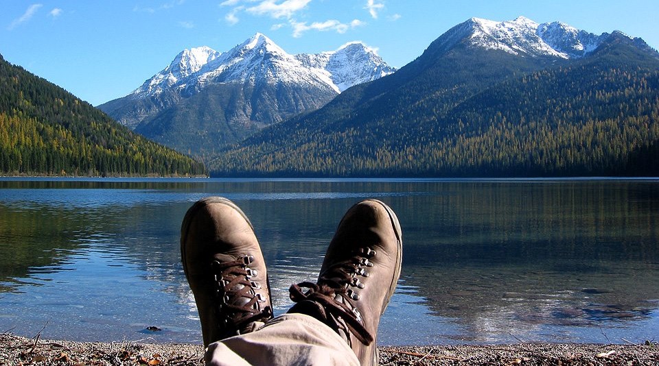 crossed boot-clad feet by shore of mountain lake crossed boot-clad feet by shore of mountain lake