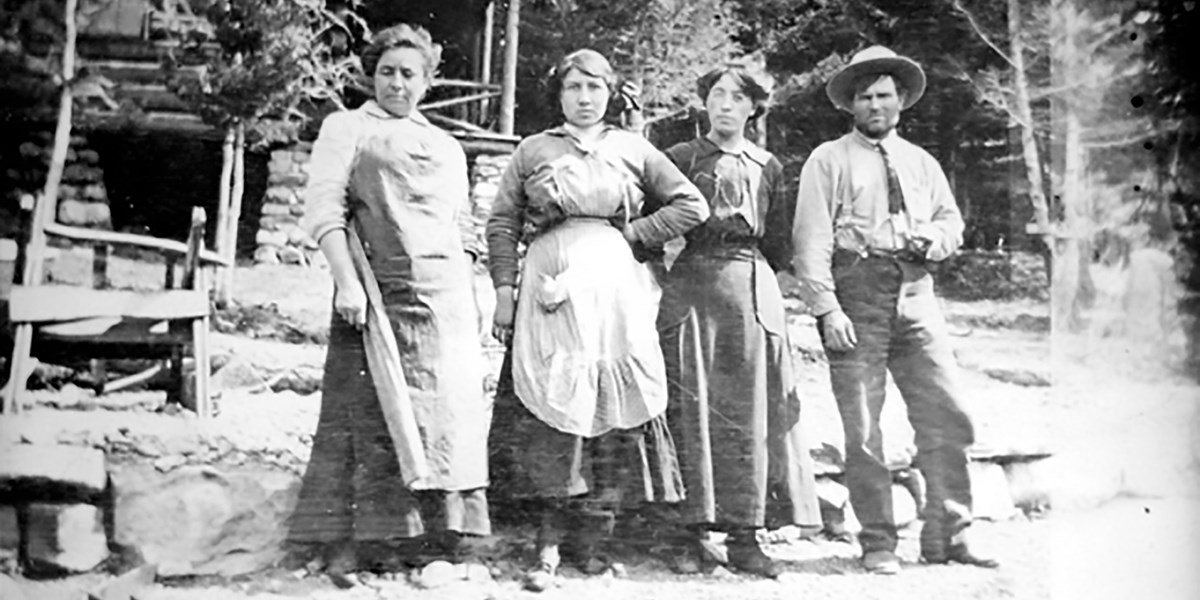 Charlie Russell stands outside his studio in Glacier, the Bullhead Lodge, with three unknown ladies
