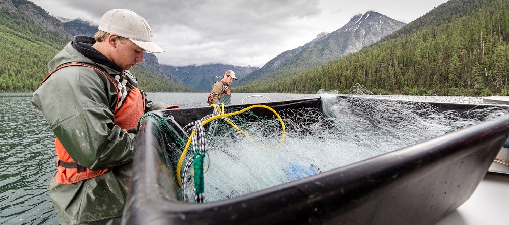 boat on mountain lake with two young men and box of fishing nets boat on mountain lake with two young men and box of fishing nets