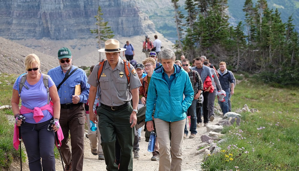 Small group discussion among hikers leading long line of people on trail