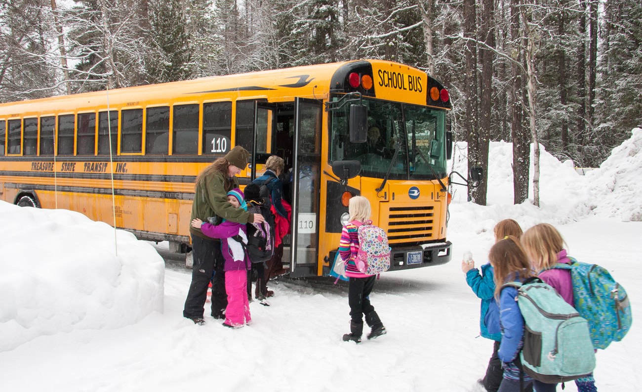 A student hugs the ranger as other students load onto the school bus.