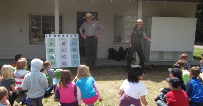 Rangers with homemade jeopardy board in front of students seated on lawn Rangers with homemade jeopardy board in front of students seated on lawn