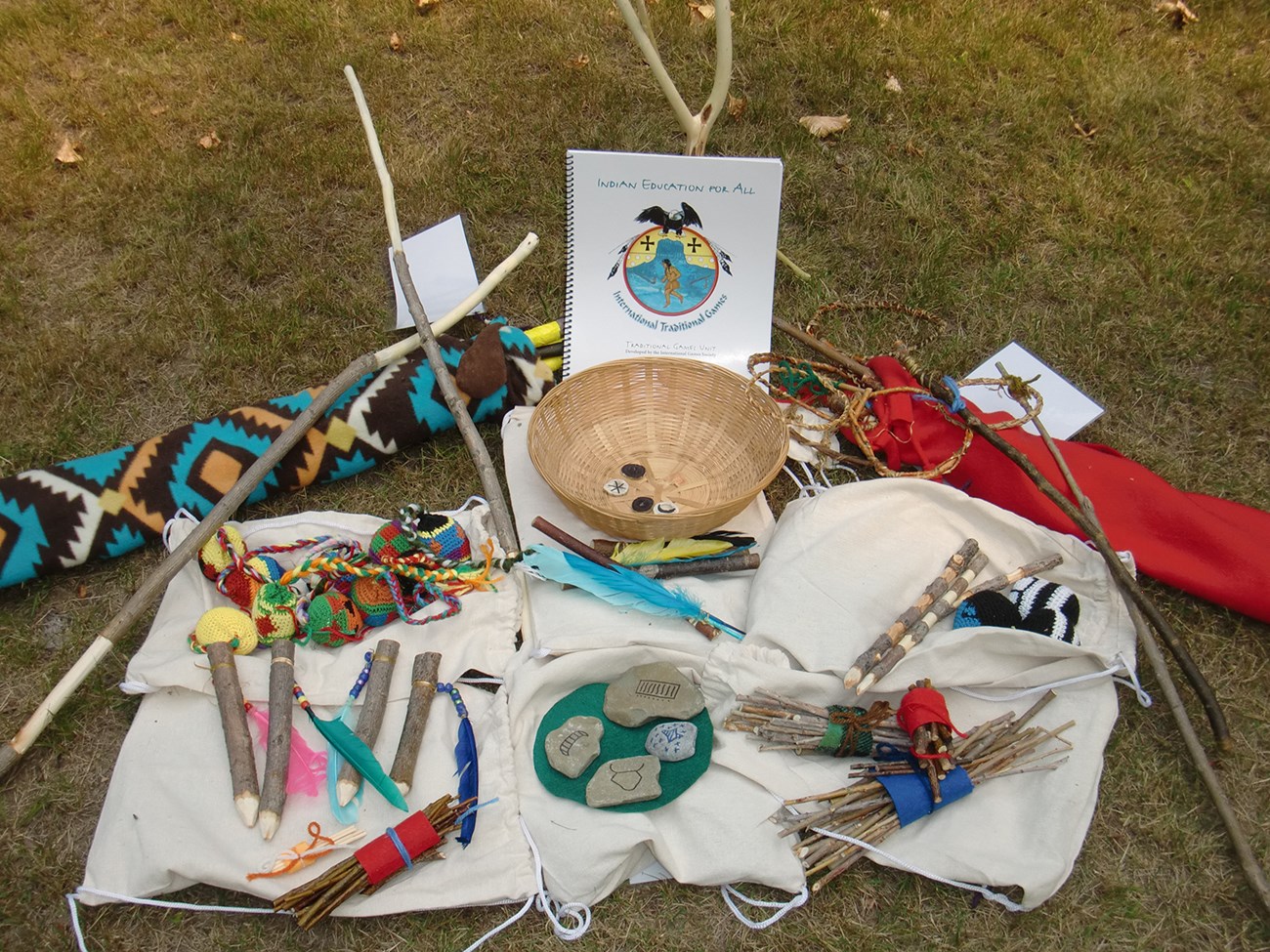 basket, sticks, antlers, and other game pieces arranged on grass