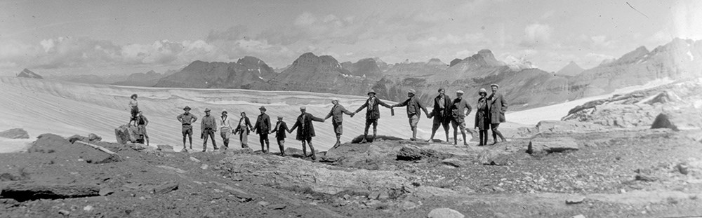 historic photo of line of hikers holding hands