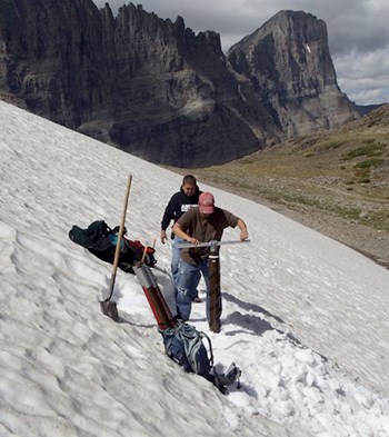 Two men on snowfield drilling