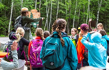 Group faces ranger holding arrowhead as she points to student with raised hand