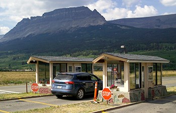 Car in lane between fee booths; mountain in background