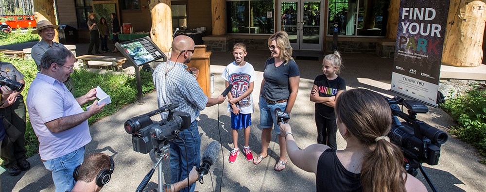 media crew holds microphones at smiling visitors