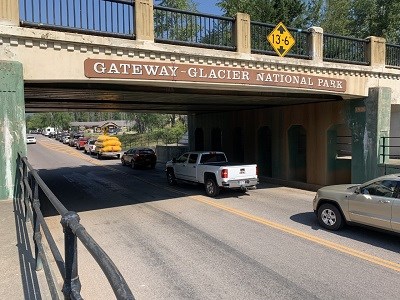 Line of cars under bridge going into the park.