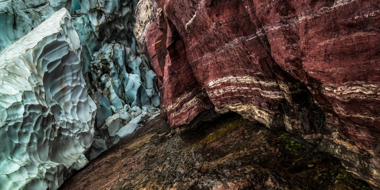 Red rocks jumble and meet with blue snow and ice.