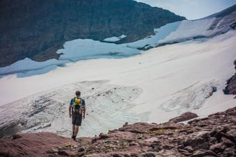 A person stands in front of a glacier.