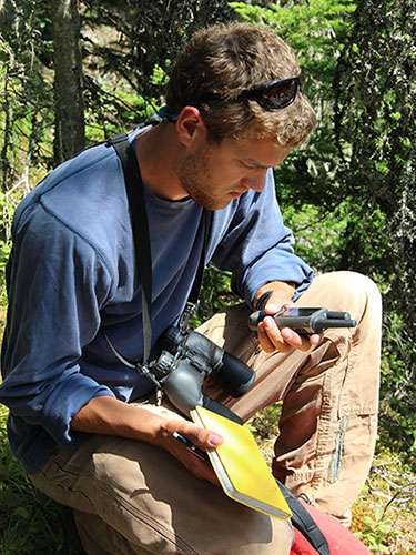 researcher with binoculars, GPS device, and field journal researcher with binoculars, GPS device, and field journal