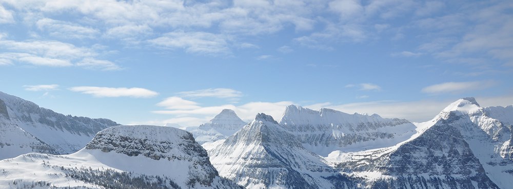 partly cloudy blue sky above snowy, sunlit peaks partly cloudy blue sky above snowy, sunlit peaks