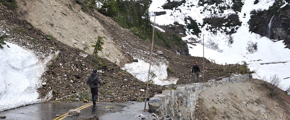 debris and snow piled on road in front of workers