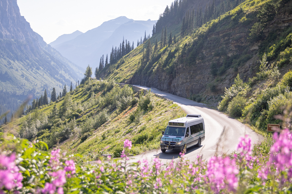 A shuttle bus drives on a mountain road.