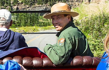 Uniformed man turns around in front seat of historic car