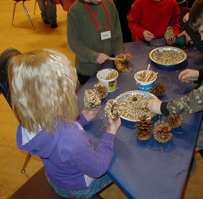 Child making a pine cone bird feeder Child making a pine cone bird feeder