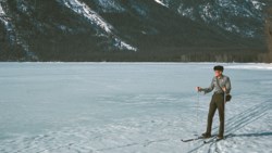Park ranger skiing across frozen lake.