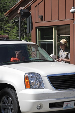 Driver in SUV hands pass to ranger in fee booth Driver in SUV hands pass to ranger in fee booth