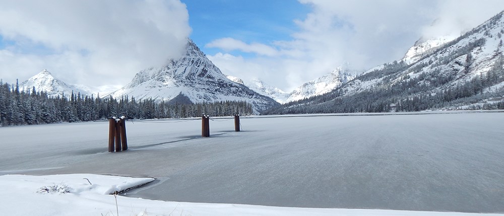 frozen mountain lake with dock pylons sticking out of ice