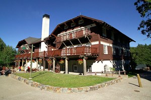 Large building with wood top, stone bottom, many balconies, and chimney in center