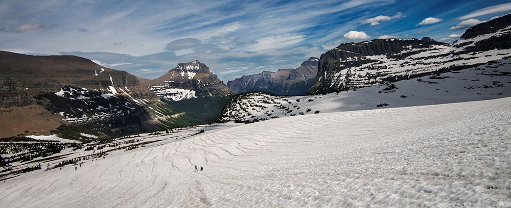 snowfield in mountains with faraway people walking on snow