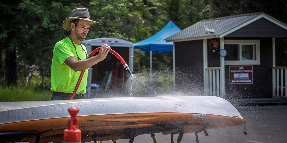 park staff hosing off a kayak at the AIS permit station in Apgar