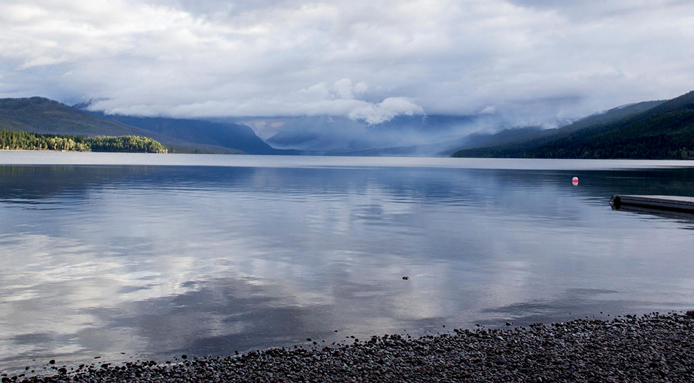 Morning clouds reflect off Lake McDonald with pockets of smoke rising from the mountains to the south Morning clouds reflect off Lake McDonald with pockets of smoke rising from the mountains to the south