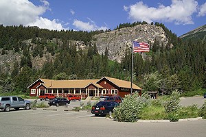 Long brown building with flagpole and parking lot in front