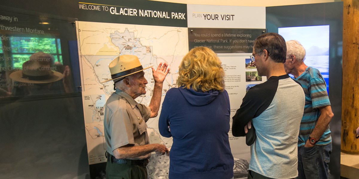 A ranger talks to visitors inside a visitor center in front of a map.