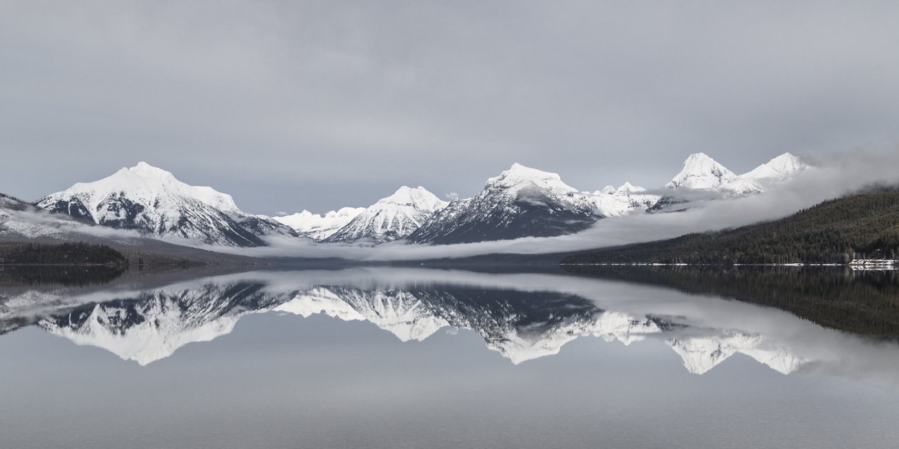 The snow-covered skyline of mountains behind Lake McDonald in winter
