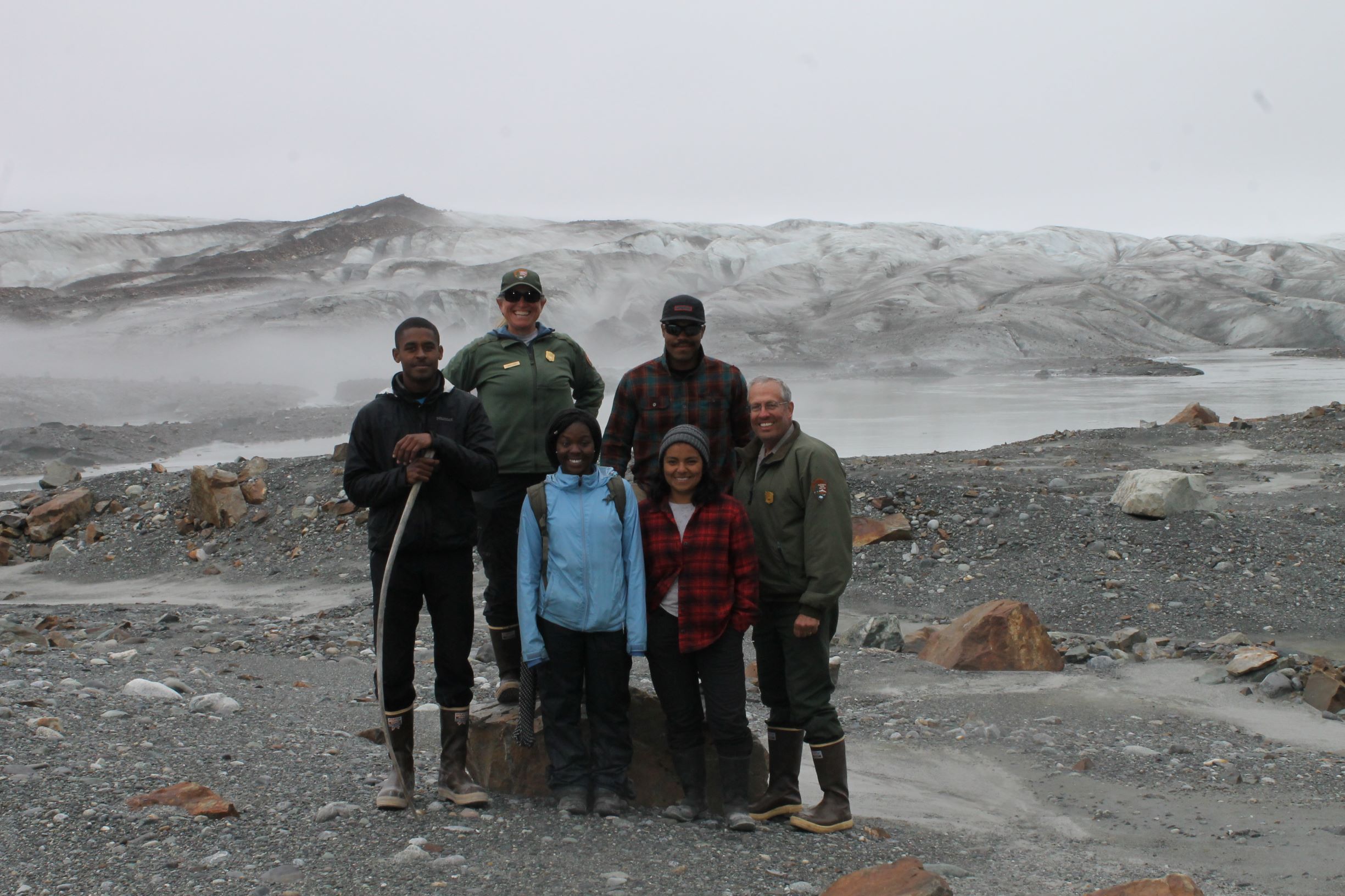 Students and NPS employees pose in front of a glacier.