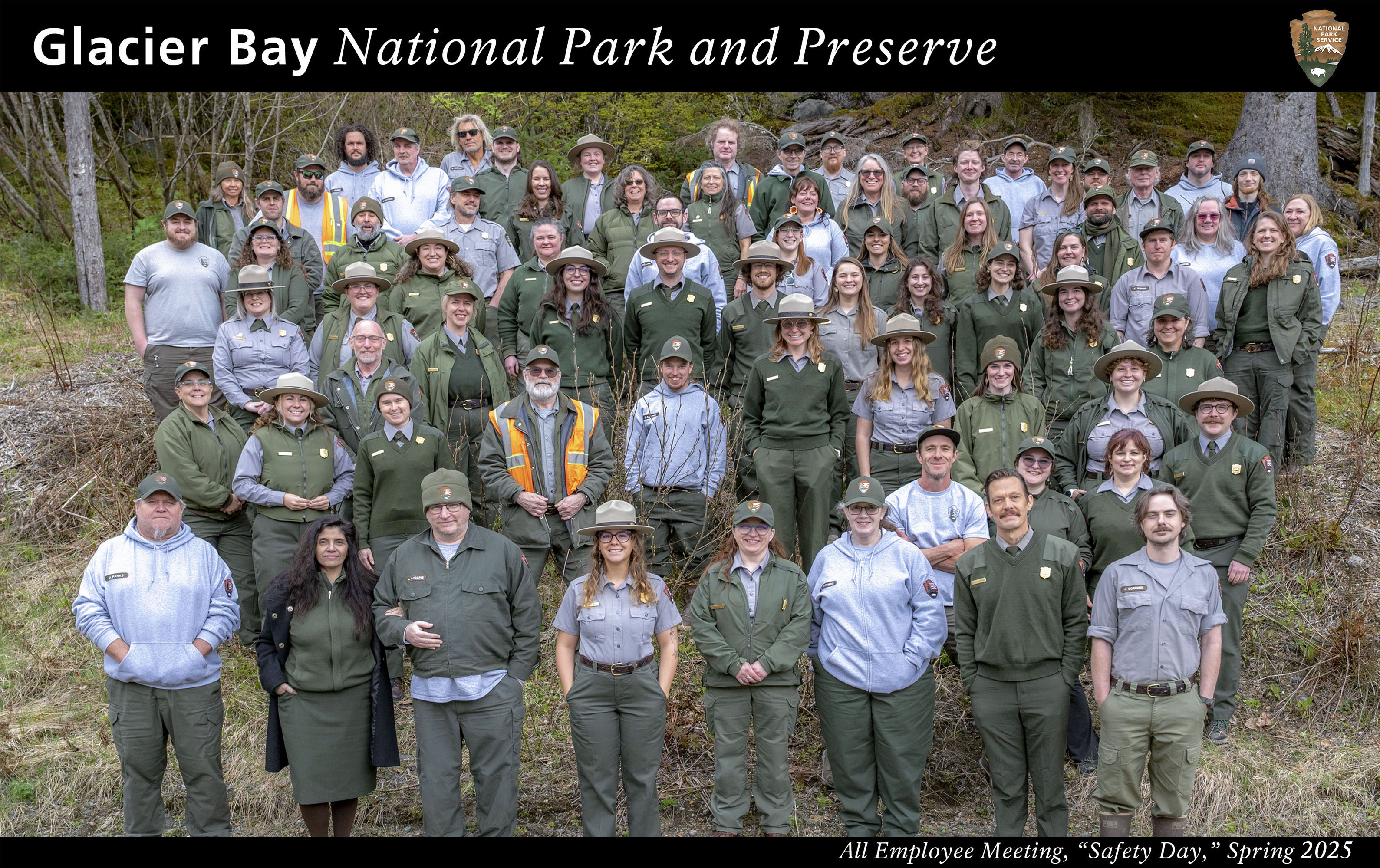 Glacier Bay staff spring 2025. Several dozen staff members stand in front of the Huna Tribal House interior screen. Text reads Glacier Bay National Park and Preserve, all employee meeting spring 2025.