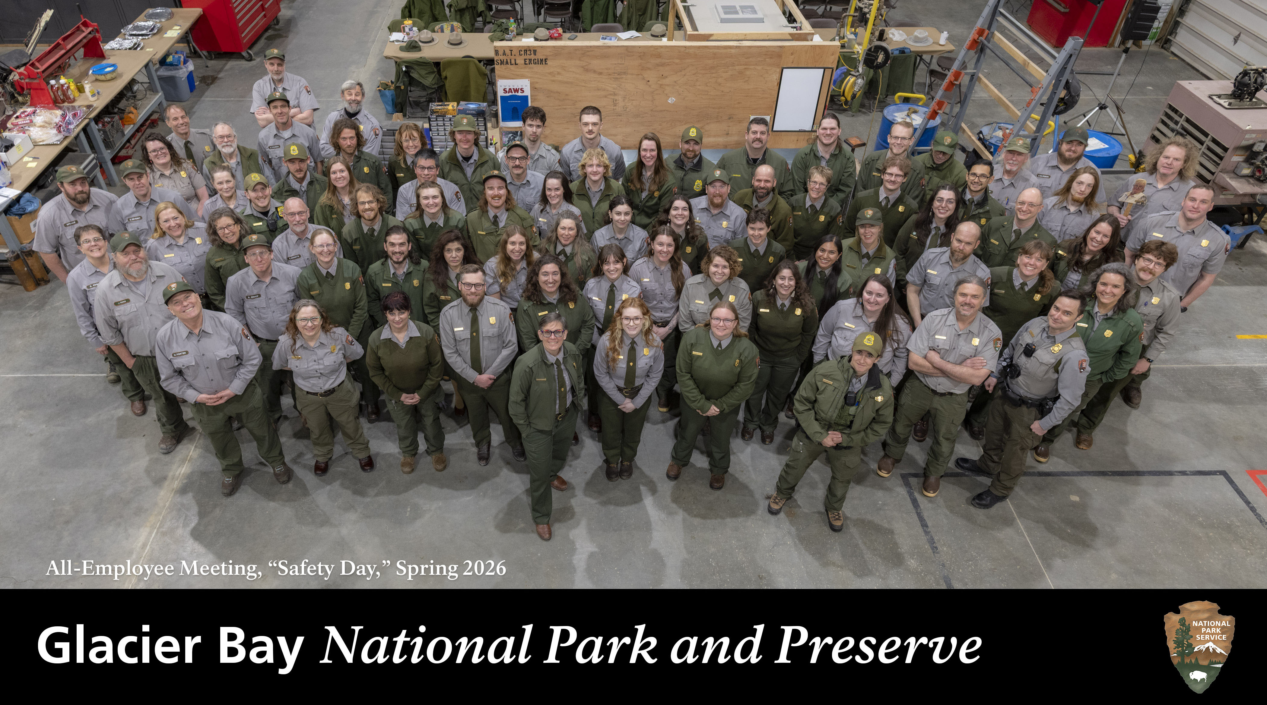 National park employees in uniform grouped together and looking upwards at the camera, smiling. Text on the image reads, "all-employee, 'safety day', spring 2026" and includes the Glacier Bay title bar and NPS arrowhead logo.