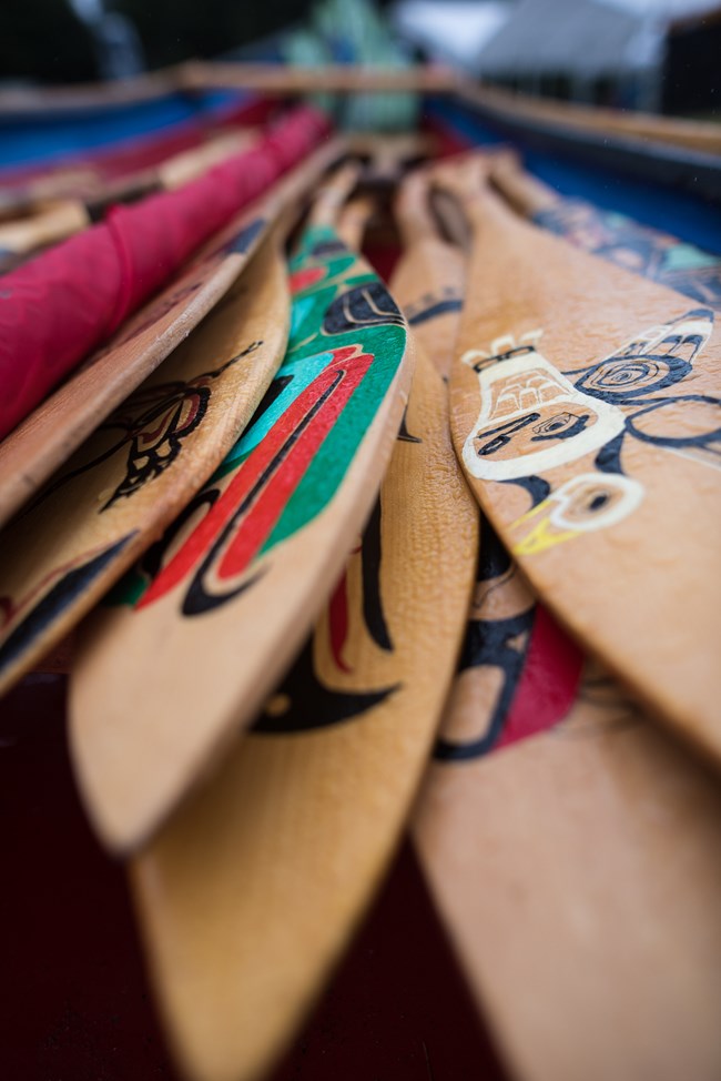 Tlingit Paddles A stack of wooden boat paddles painted with Tlingit designs.