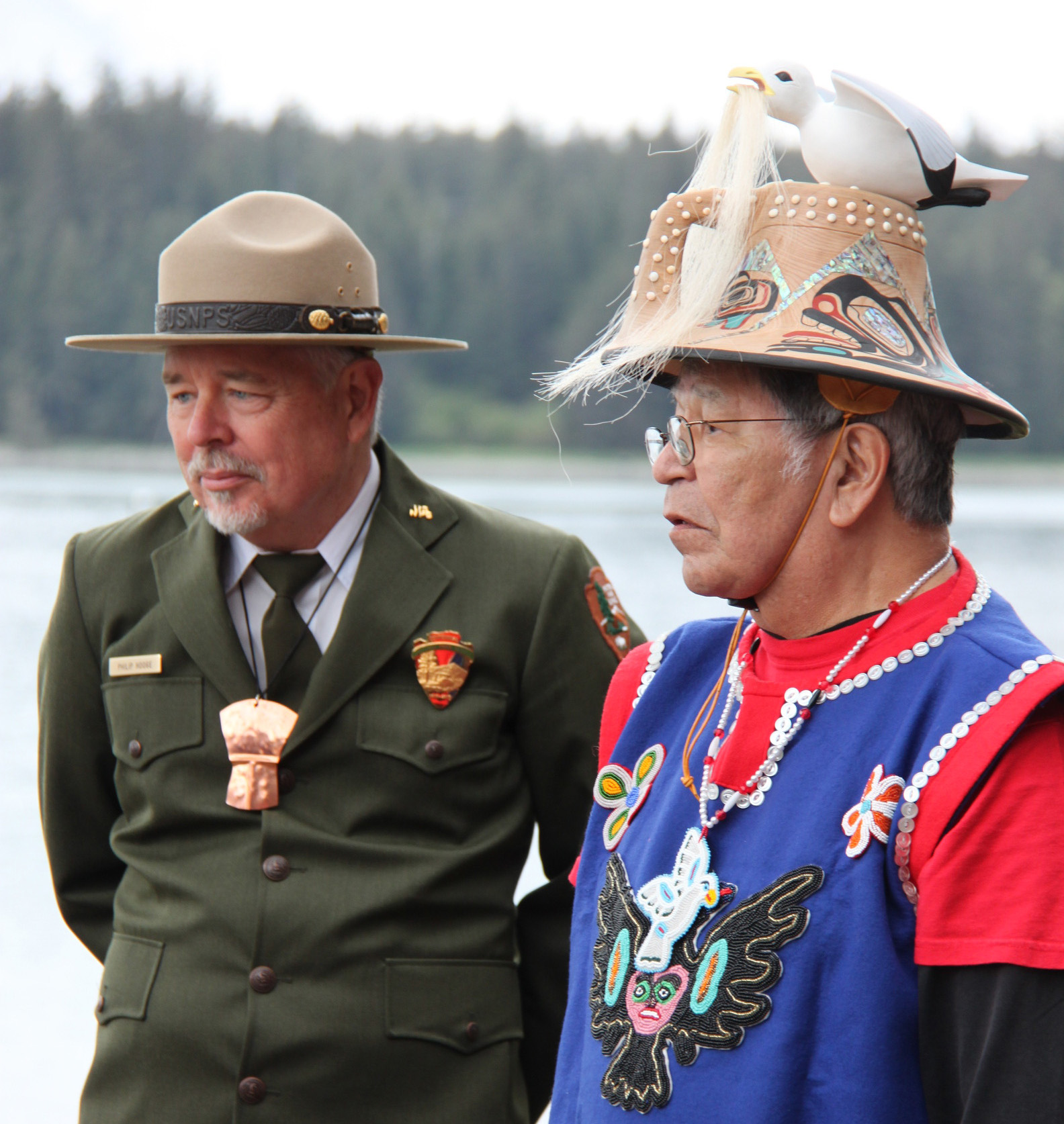 Elder Ken Grant in Łingít regalia standing beside National Park Service superintendent in uniform.