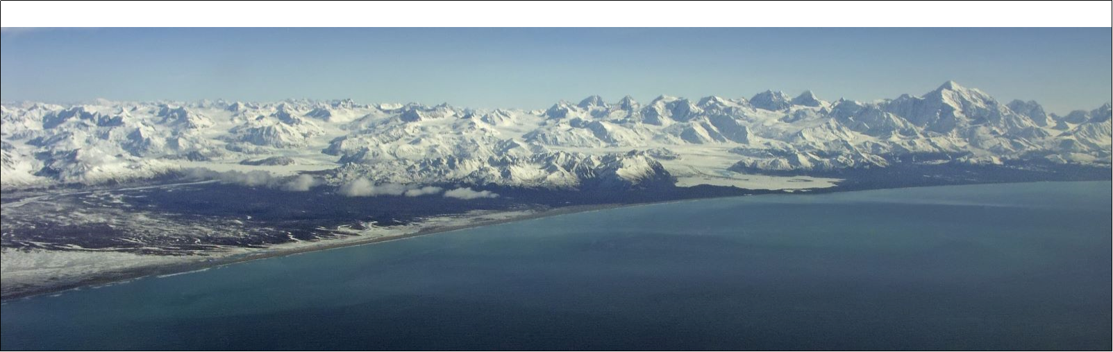 Fairweather Range with many snow-capped mountains and a gulf in foreground