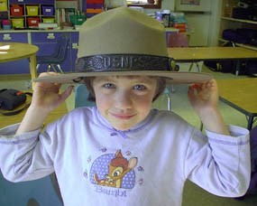 New JR Ranger a child holds a NPS flathat on her head