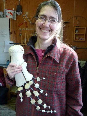 Smiling volunteer holds up whale flipper skeleton after pieces have been assembled and articulated into position.