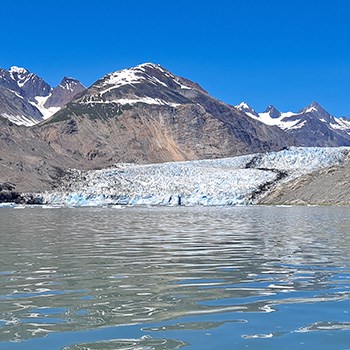 mcbride glacier is strikingly white and blue between steep brown rugged mountains.