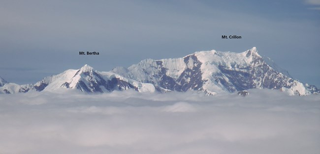 Two mountain peaks with snow and clouds